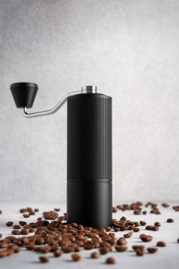 Açık arkaplanda kahve çekirdekleri olan siyah bir el değirmeni. Kahve ayinini, sakin işçiliği, hassasiyeti ve modern günlük basitliği vurgulayan temiz, sade bir hayat..