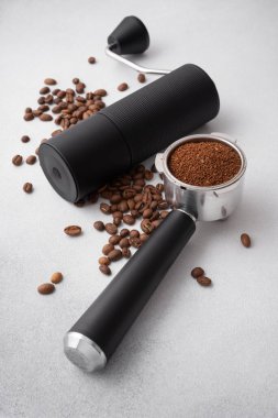 Elle kahve öğütücü, kavrulmuş fasulye ve hafif arka planda öğütülmüş kahve ile doldurulmuş portafilter. Özel kahve, ustalık, hassasiyet ve dikkatli demleme ritüeli kavramı..