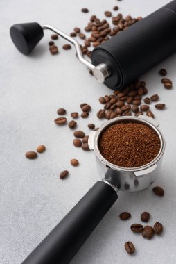 Elle kahve öğütücü, kavrulmuş fasulye ve hafif arka planda öğütülmüş kahve ile doldurulmuş portafilter. Özel kahve, ustalık, hassasiyet ve dikkatli demleme ritüeli kavramı..