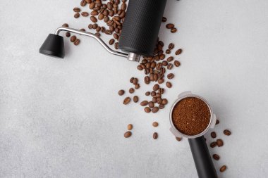 Elle kahve öğütücü, kavrulmuş fasulye ve hafif arka planda öğütülmüş kahve ile doldurulmuş portafilter. Özel kahve, ustalık, hassasiyet ve dikkatli demleme ritüeli kavramı..