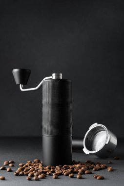 El yapımı kahve öğütücü ve koyu arkaplanda kavrulmuş fasulyeli espresso filtresi. Minimum lüks hala kahve ritüeli, işçilik, hassasiyet ve odaklanmış analog yaşam tarzı vurguluyor..