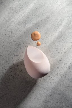 Makyaj süngeri ve temeli dokulu arka planda asgari güzellik kompozisyonu. Doğal cilt bakımı, yumuşaklık, temiz güzellik, sağlık rutini ve modern kozmetik estetiği kavramı..