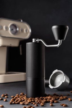Arka planda espresso kahve makinesi olan siyah el yapımı kahve öğütücüsü. Özel kahveyi, zanaatkarlığı, dikkatli ritüeli, kaliteli birayı ve ev kahvecisi yaşam tarzını simgeleyen minimum sade yaşam..