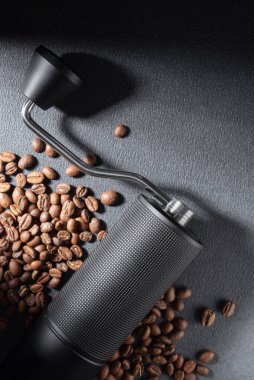 Koyu dokulu arkaplanda kavrulmuş fasulye ile elle kahve öğütücü. Huysuz dramatik ışıklandırma, kahve hazırlamada işçilik, ritüel ve kontrolün altını çizer. Özel kahve ve yaşam tarzı kavramları için ideal..