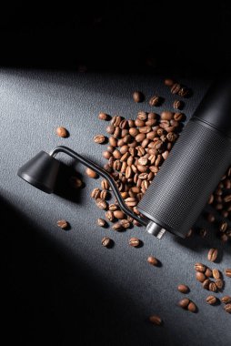 Koyu dokulu arkaplanda kavrulmuş fasulye ile elle kahve öğütücü. Huysuz dramatik ışıklandırma, kahve hazırlamada işçilik, ritüel ve kontrolün altını çizer. Özel kahve ve yaşam tarzı kavramları için ideal..