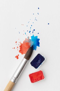 Kırmızı ve mavi boyalı suluboya fırça beyaz kağıda sıçramış. Minimum sanatsal durağan hayat yaratıcılığı, ifadeyi, seçimi, kontrastı, ilhamı ve yaratıcı süreci sembolize eder.