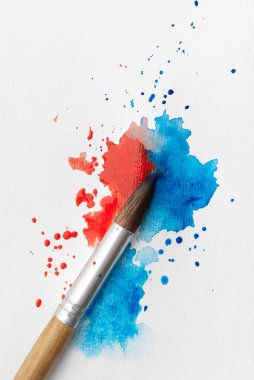 Kırmızı ve mavi boyalı suluboya fırça beyaz kağıda sıçramış. Minimum sanatsal durağan hayat yaratıcılığı, ifadeyi, seçimi, kontrastı, ilhamı ve yaratıcı süreci sembolize eder.