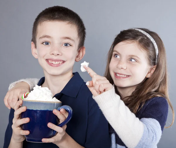 熱いココア マグカップからホイップ クリームを彼女の兄をからかう女の子 — ストック写真