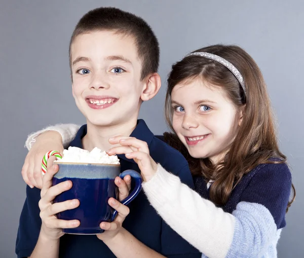 Girl teasing her brother with whipped cream from a hot cocoa mug — Stock Photo, Image