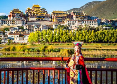 Shangrila China, 8 Ekim 2020: Songzanlin Manastırı önünde poz veren geleneksel elbiseli kadın Şangri-La Yunnan Çin 'de gün batımında