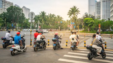 Haikou China, 21 Mart 2021: Hainan Çin 'deki modern Haikou caddesinde scooter kullanan insanlar
