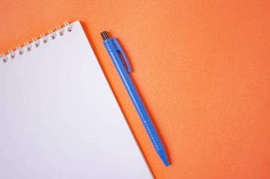 Turuncu arkaplanda kalem ve defter