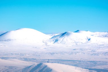 Kar beyazı tarlalar, dağlar ve mavi gökyüzü