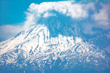 Bulutlarla kaplı karlı dağ tepesi. Karla kaplı güzel bir dağ.