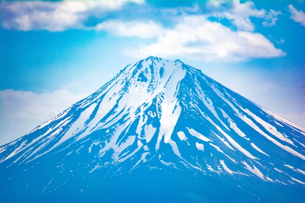 Bulutlarla kaplı karlı dağ tepesi. Karla kaplı güzel bir dağ.