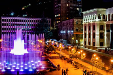 Şehir meydanında fıskiyeler. Renkli çiçeklerle dolu bir gece meydanı. Gece şehri Kapan.