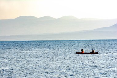 Denizin dalgalarında bir sandalda iki kişi. İki sporcu bir tekneyle denize açıldılar.