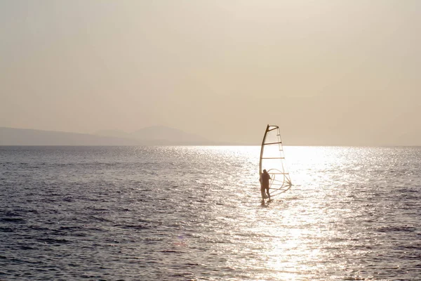 Water sports. Windsurfing on the blue sea. Windsurfer in the middle of the sea. Windsurfing athlete