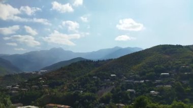 Hareket eden beyaz bulutlarla dağların üzerinden zaman geçiyor. Mavi gökyüzü, yüksek dağ ve beyaz bulutlar