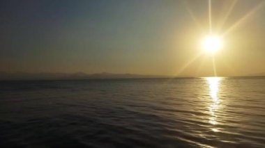 Denizin üzerinde güzel bir gün batımı. Deniz manzarası ve günbatımı. Büyük güneş ufukta beliriyor. Turuncu gün batımı, mavi deniz ve mavi deniz suları. Jet ski 'ler denize açılır.