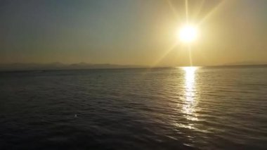 Deniz manzarası ve günbatımı. Büyük güneş ufukta beliriyor. Turuncu gün batımı, mavi deniz ve mavi deniz suları