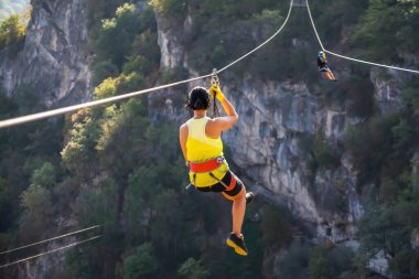 Eğlence, adrenalin ve teleferik hattında macera. Ergen, panoramik orman arka planında zeplinle eğleniyor. Ormanda halatla kayma. İnsanlar ormandaki halatla adrenalin salgılar.