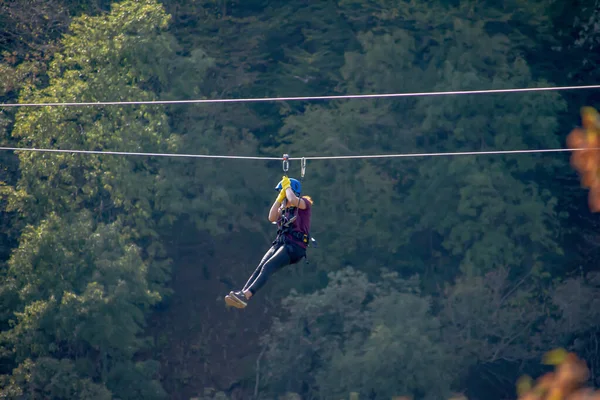 Eğlence, adrenalin ve teleferik hattında macera. Ergen, panoramik orman arka planında zeplinle eğleniyor. Ormanda halatla kayma. İnsanlar ormandaki halatla adrenalin salgılar.