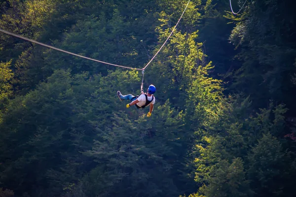 Eğlence, adrenalin ve teleferik hattında macera. Ergen, panoramik orman arka planında zeplinle eğleniyor. Ormanda halatla kayma. İnsanlar ormandaki halatla adrenalin salgılar.