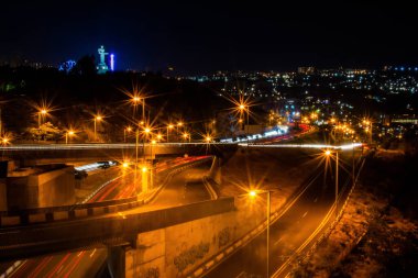 Gece şehrinde renkli araba trafiği. Köprüdeki arabaların hareketi. Otobanda gece trafiği. Gece şehrinin aydınlık yolları. Gece şehir hayatı