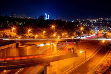 Geceleri otobanlarda araba trafiği. Köprüdeki arabaların hareketi. Güzel mimarisi ve anıtları olan bir gece şehri. Gece şehrinin aydınlık yolları. Gece şehir hayatı