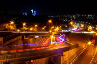 Gece şehrinde renkli araba trafiği. Köprüdeki arabaların hareketi. Otobanda gece trafiği. Gece şehrinin aydınlık yolları. Gece şehir hayatı