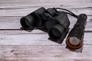 Dürbün ve ahşap bir masada el feneri. Siyah dürbün, siyah el feneri..