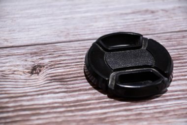 Ahşap arka planda siyah lens kapağı. Kaputlar ve kapaklar