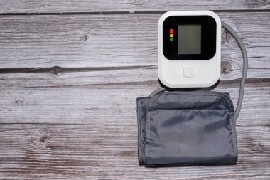 Tansiyonu ölçmek için bir tonometre. Masadaki elektrikli tonometre. Bir insanın kan basıncını ölçüyor. Ahşap desenli arka planda bir tonometre 