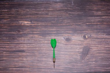 Ahşap arka planda yeşil dart. İş konsepti. Seçici odaklanma. Masada dart oku.