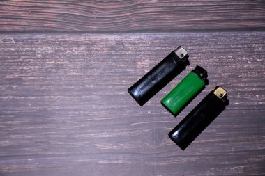 Ahşap arka planda daha hafif. Üst Manzara. Çakmaklar masaya. Sigaraya karşılık ateş.