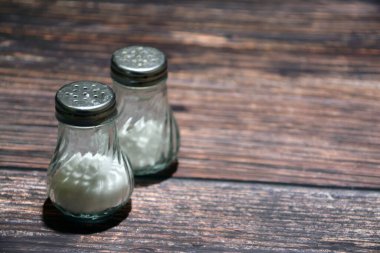 Masada bir şişe tuz. Ahşap arka planda tuzluk ve biberlik. Seçici odak.