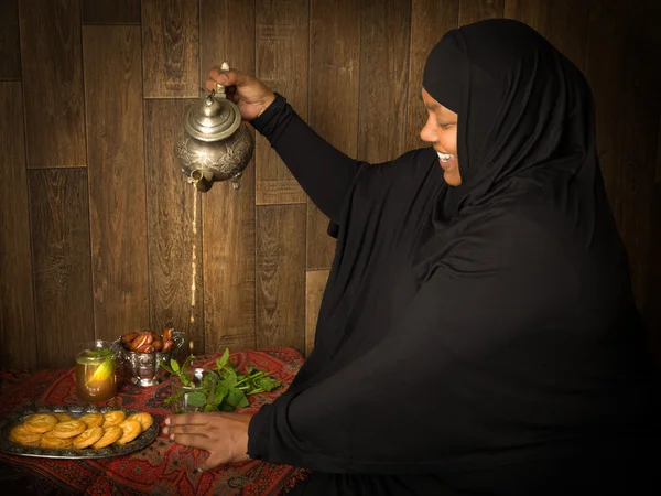 Mulher muçulmana derramando chá — Fotografia de Stock