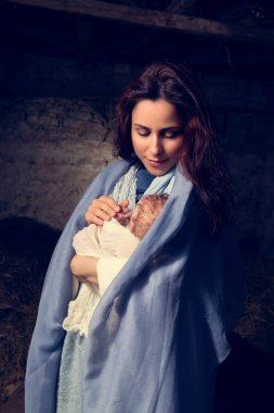 Eski bir ahırda Noel İsa 'nın doğumu sahnesi gerçek kostümlerle canlandırılıyor. Bebek bir oyuncak bebek..