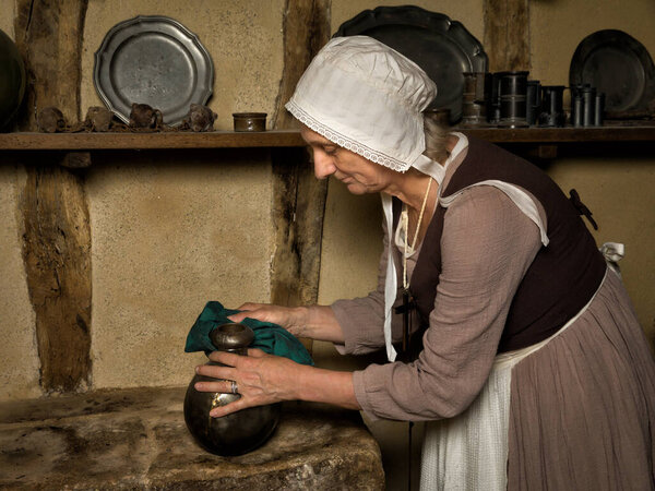 Woman dressed as a medieval peasant maid working in an authentic kitchen in a French castle