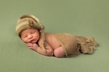 7 günlük yeni doğmuş bebek yumuşak yeşil bir battaniyenin üzerinde uyuyor.