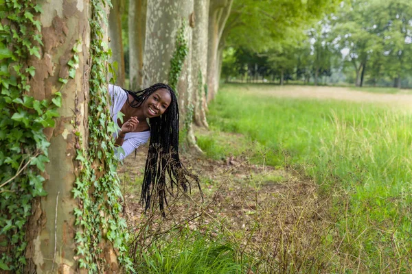 Pretty Young African Woman Black Braids Hiding Playful Big Trees — Stock Photo, Image