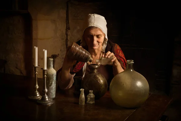 在法国中世纪城堡的厨房里担任炼金术士或女巫的身着中世纪服装的妇女 可以获得财产释放 — 图库照片