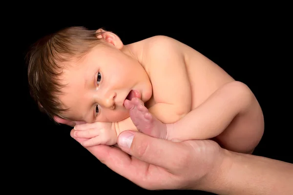 Bebé recién nacido chupando en el dedo del pie — Foto de Stock