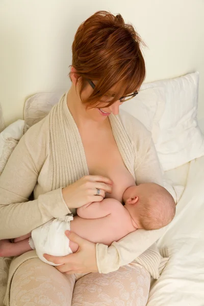 Mãe alimentando bebê na cama — Fotografia de Stock