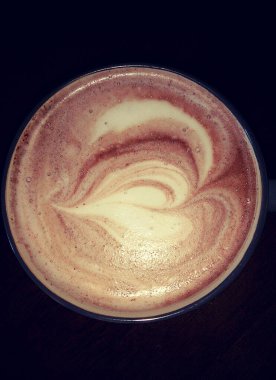 Koyu arkaplanlı bir fincan kahvenin hemen üstünde. Kalp şekli.