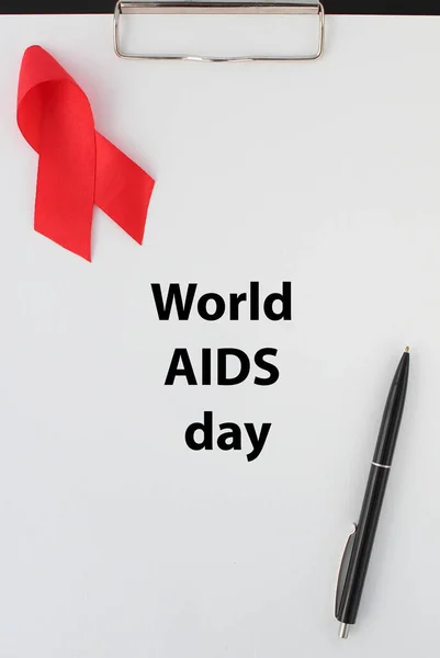 Beyaz kağıt üzerinde kırmızı kurdele ve Dünya AIDS Günü