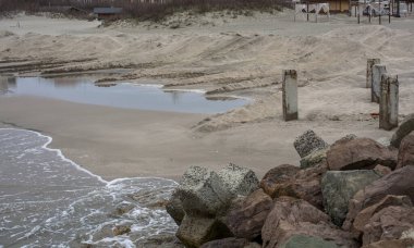 Issız bir sahile yakından bakmak kayalar, beton sütunlar ve kum seti. Pomorie tatil beldesi, Bulgaristan