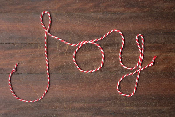 Xmas word "joy" written in red and white striped string — Stock Photo, Image
