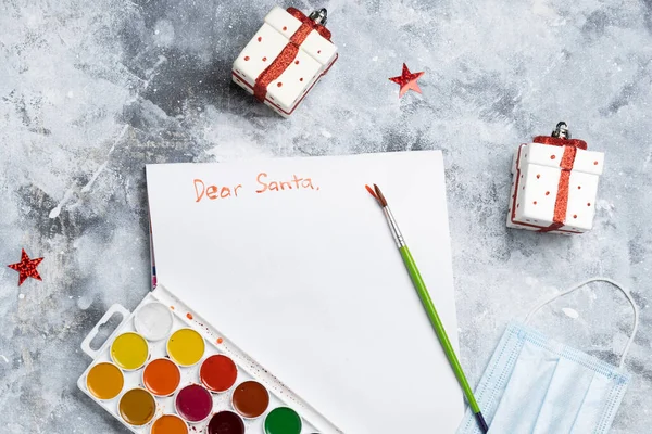 Yılbaşı süslemeleri ve gri arka planda maskeli Noel Baba mektupları.